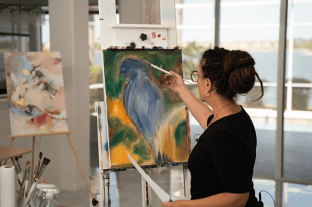 woman blocking in paint on a canvas blue green yellow