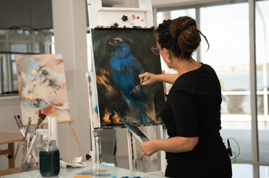 woman painting on canvas blue bird