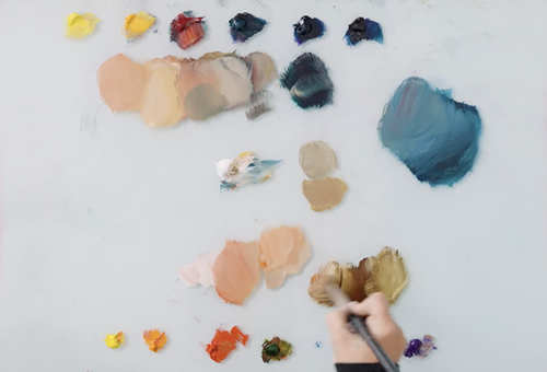 hand with paintbrush on colorful pallet