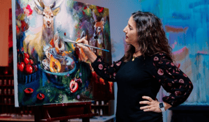 Woman sitting in front of fireplace with artwork canvases