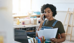 female reading papers in front of desk with computer