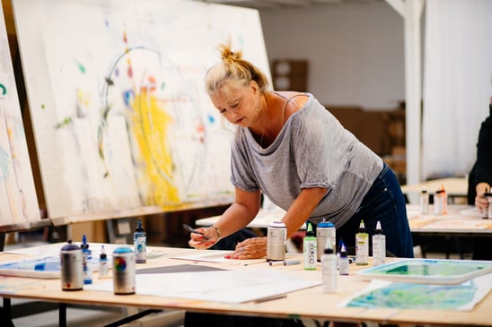 Woman standing over work table making art in studio