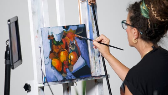 Woman in black shirt painting with oranges and mouse