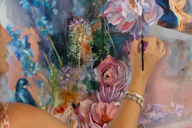 Woman painting pink flowers on canvas