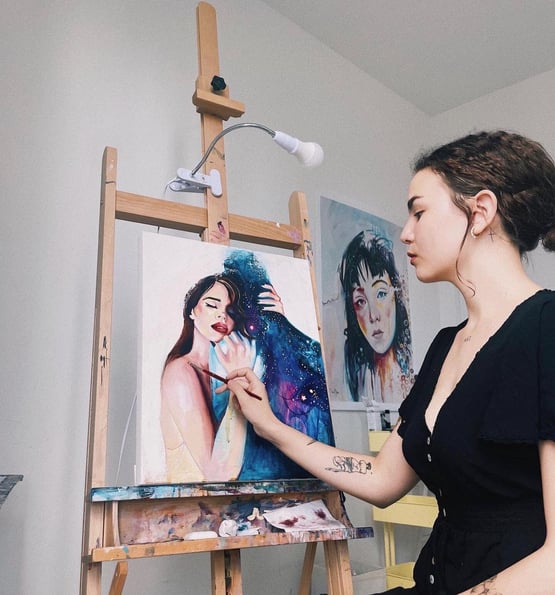 Daphny Painting a portrait on an easel with lightbulb clamp light 