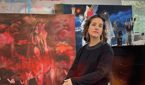 Woman standing in fornt of red horse painitng