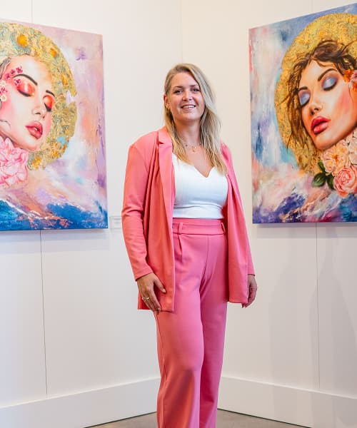 Ellis Hollering in pink standing in front of portraits