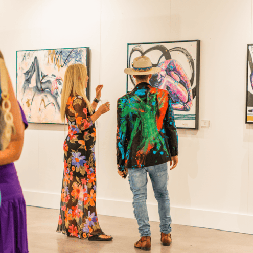 man and woman standing in front of painting of pink female figure