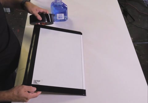 hands holding glass piece adding tape to edges