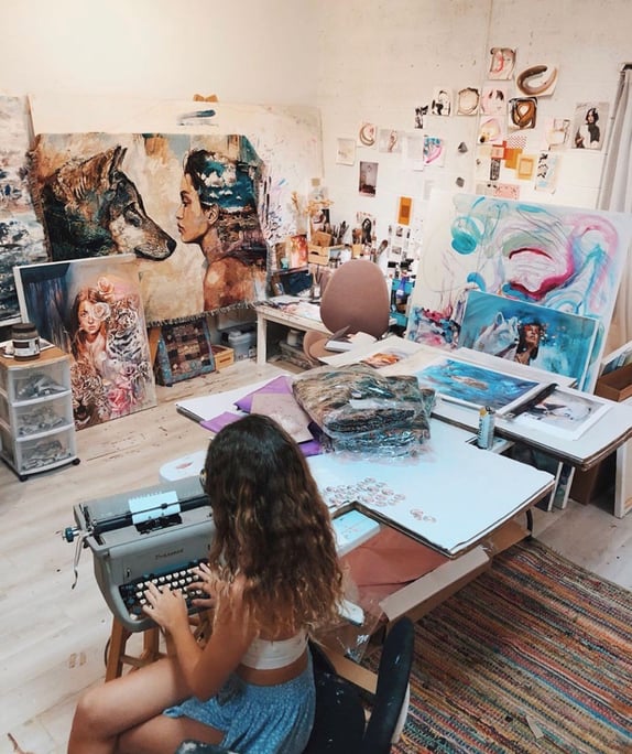 woman sitting at vintage typwriter in art studio
