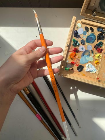 Hand holding size 6 paintbrush