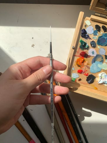 hand holding size 4 paintbrush