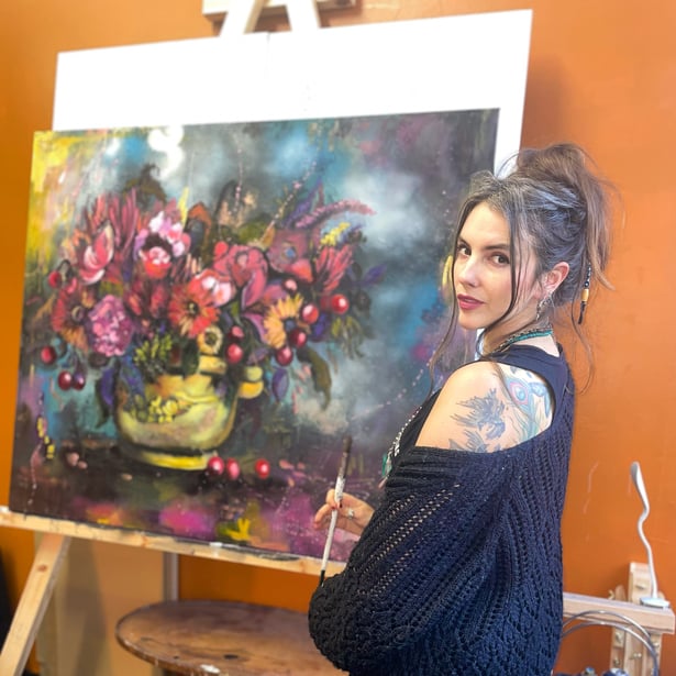 Lisa Cunningham woman in black sweater standing in front of pink and red vase of flowers on canvas