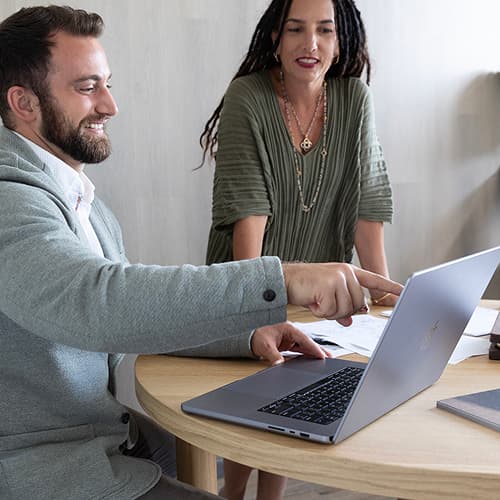 man sitting with woman pointing at computer