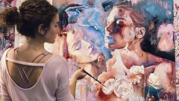woman painting portrais in pink and blue