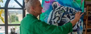 Woman painting colorful art canvas of black and white tigger on blue green paint