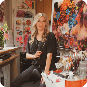Woman sitting in art studio with colorful paintings around