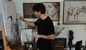 Man painting with animal art in background