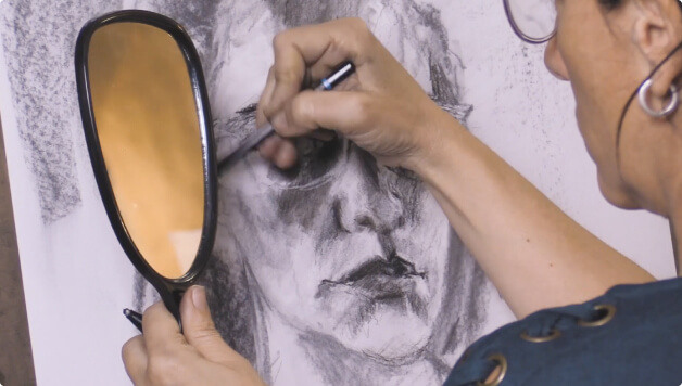 woman drawing a portait holding a mirror