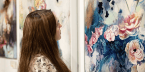 woman looking at floral painting blue