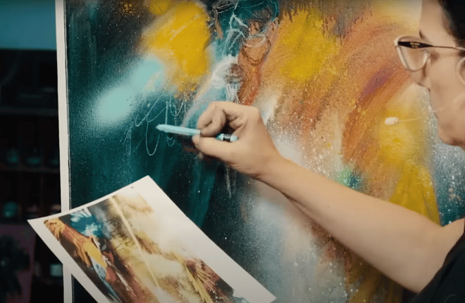 Woman drawing in front of teal and yellow canvas