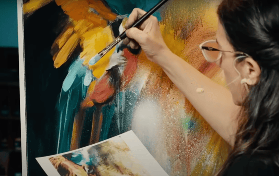 Woman painting on canvas teal and yellow and orange
