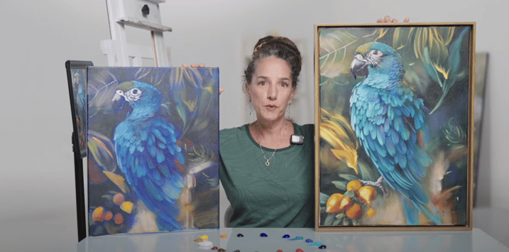 woman holding two paitings of parrots 