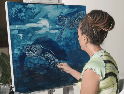woman subtracting highlights from canvas with blue oil paint turtles