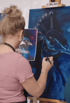Woman painter painting with paper source a blue peacock 