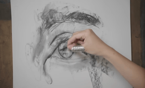 Hand sketching eye with charcoal on paper 