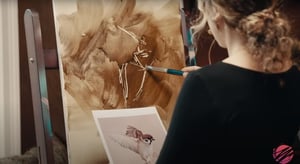 woman subtracting oil paint with tool on canvas in black shirt