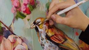 Hand painting a bird on canvas