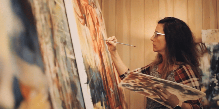 Elli Milan working on a painting yellow tones