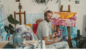 Man sitting painitng on art canvas