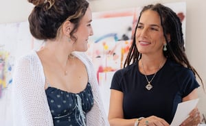 Woman looking at each other paintings in background