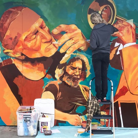 Artist paintin mural on wall blue teal orange yellow Bob Dylan