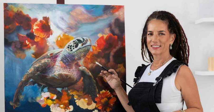 Elli Milan painting a sea turtle canvas at her easel in her studio