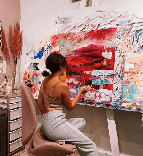 girl sitting at canvas painting abstract landscape