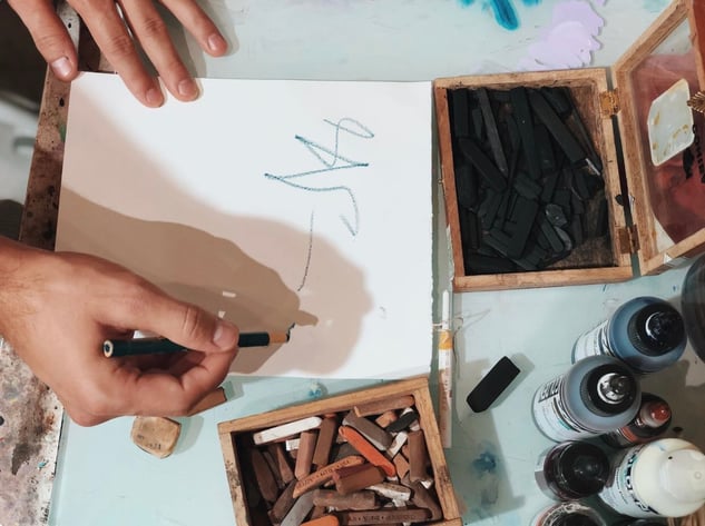 hands writing on paper with charcoal