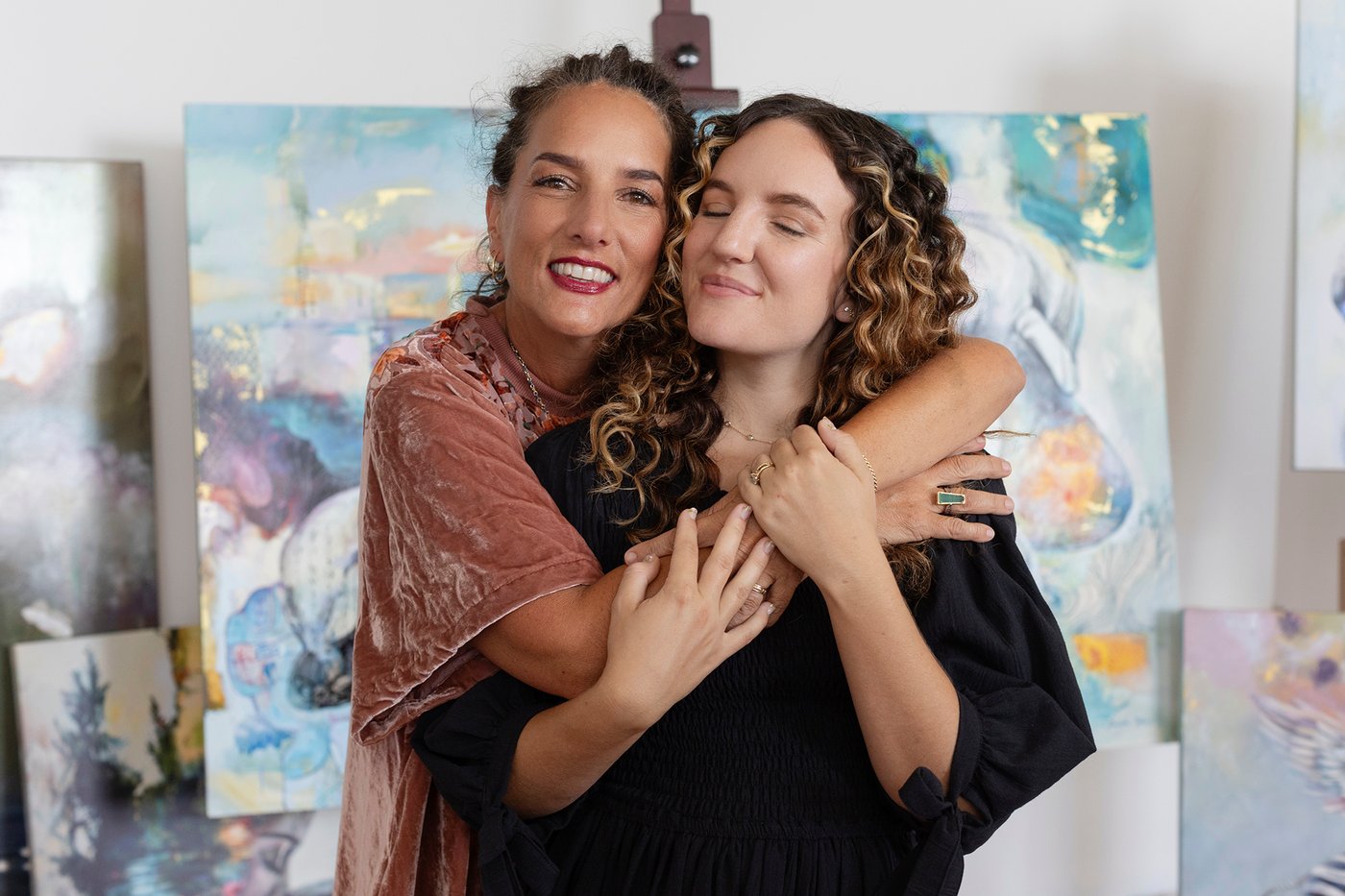 Elli Milan and Dimitra Milan in the studio, standing in front of their paintings