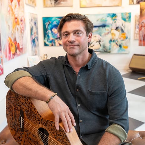 man sitting in gallery with guitar