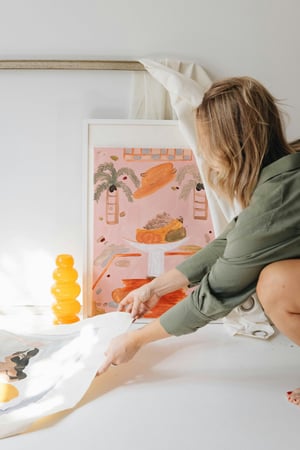Woman artist lifting up art pint pink orange in whote studio room