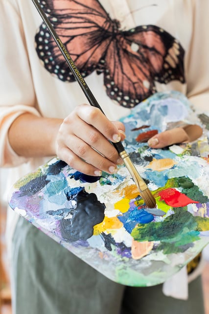 woman holding paint palette blue green red paint