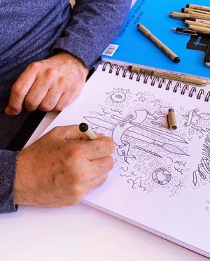 Man sketching in book with student
