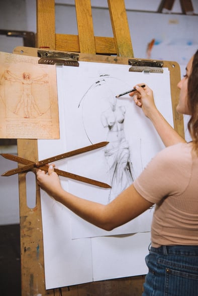 girl sketching statue drawing tan shirt wood board