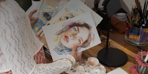 woman holding watercolor papers with portrait