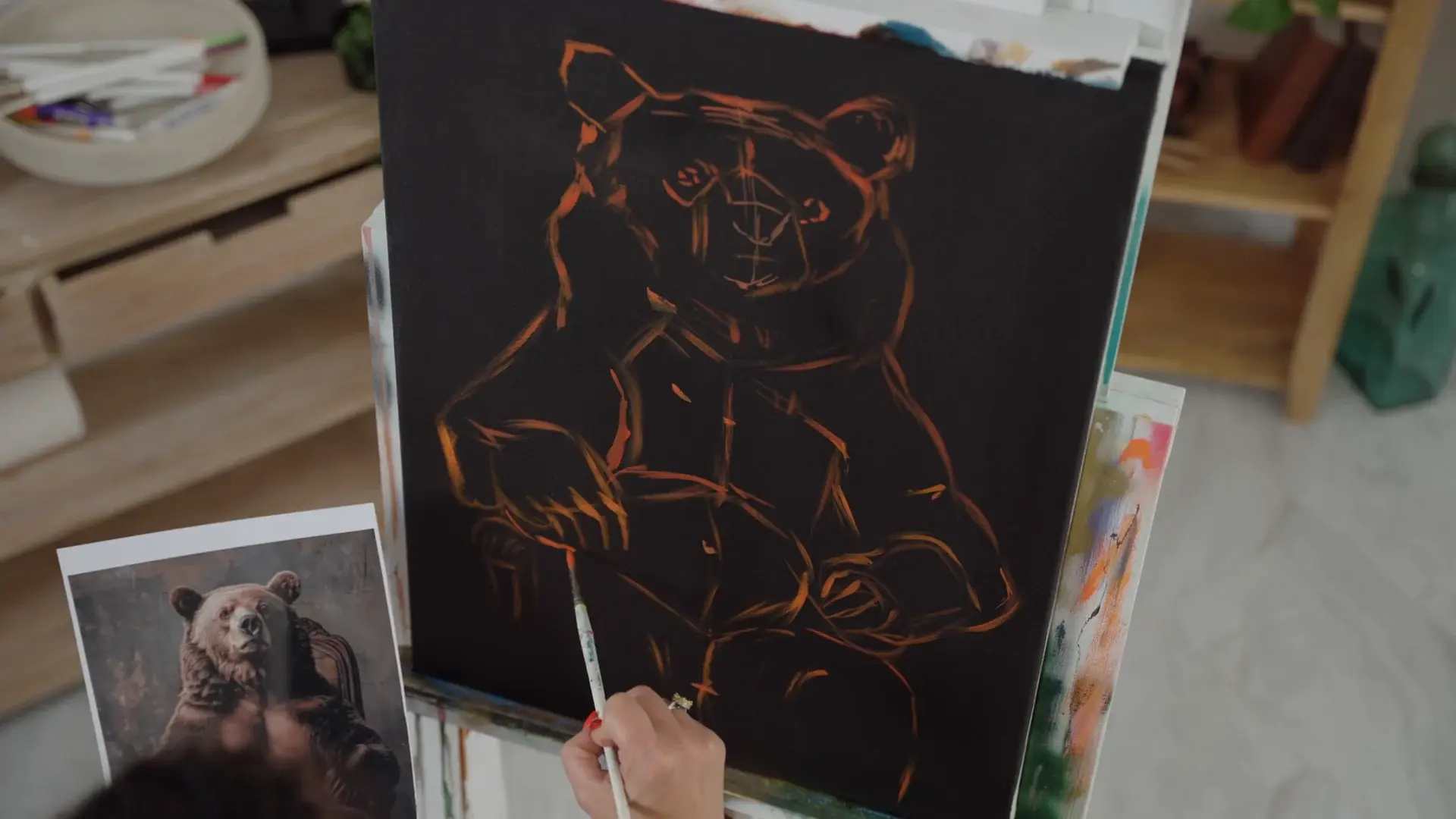 The bear drawn in thin orange lines on the black canvas