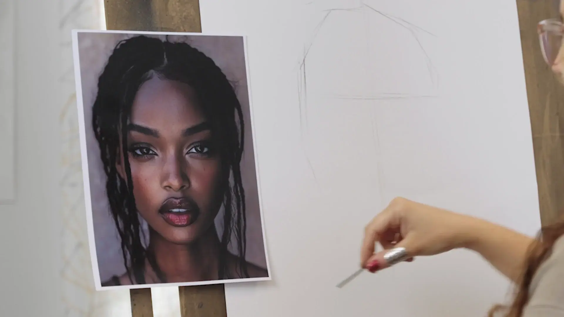 The reference photo taped beside faint first charcoal lines