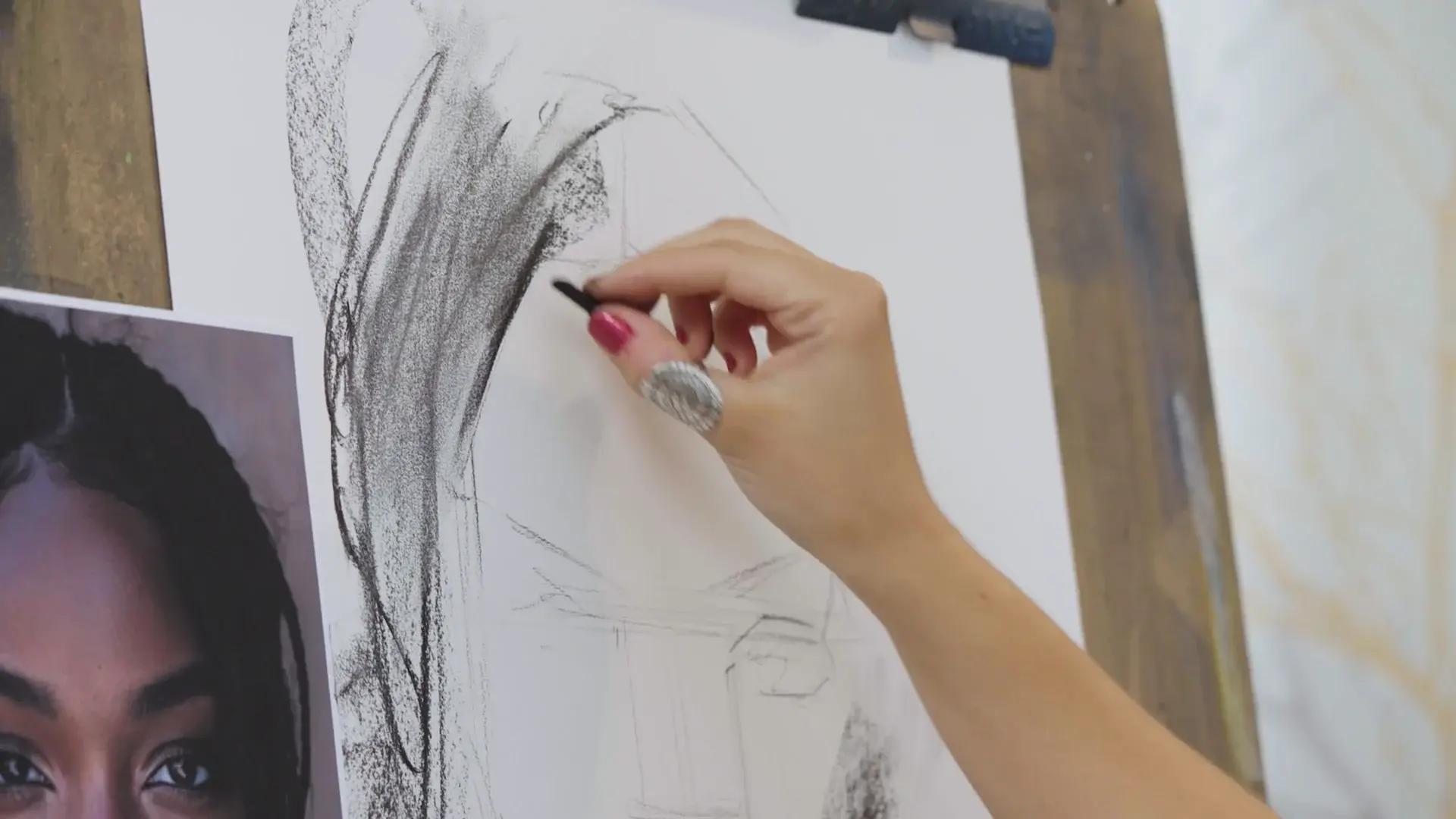 A hand laying in the dark hair with compressed charcoal