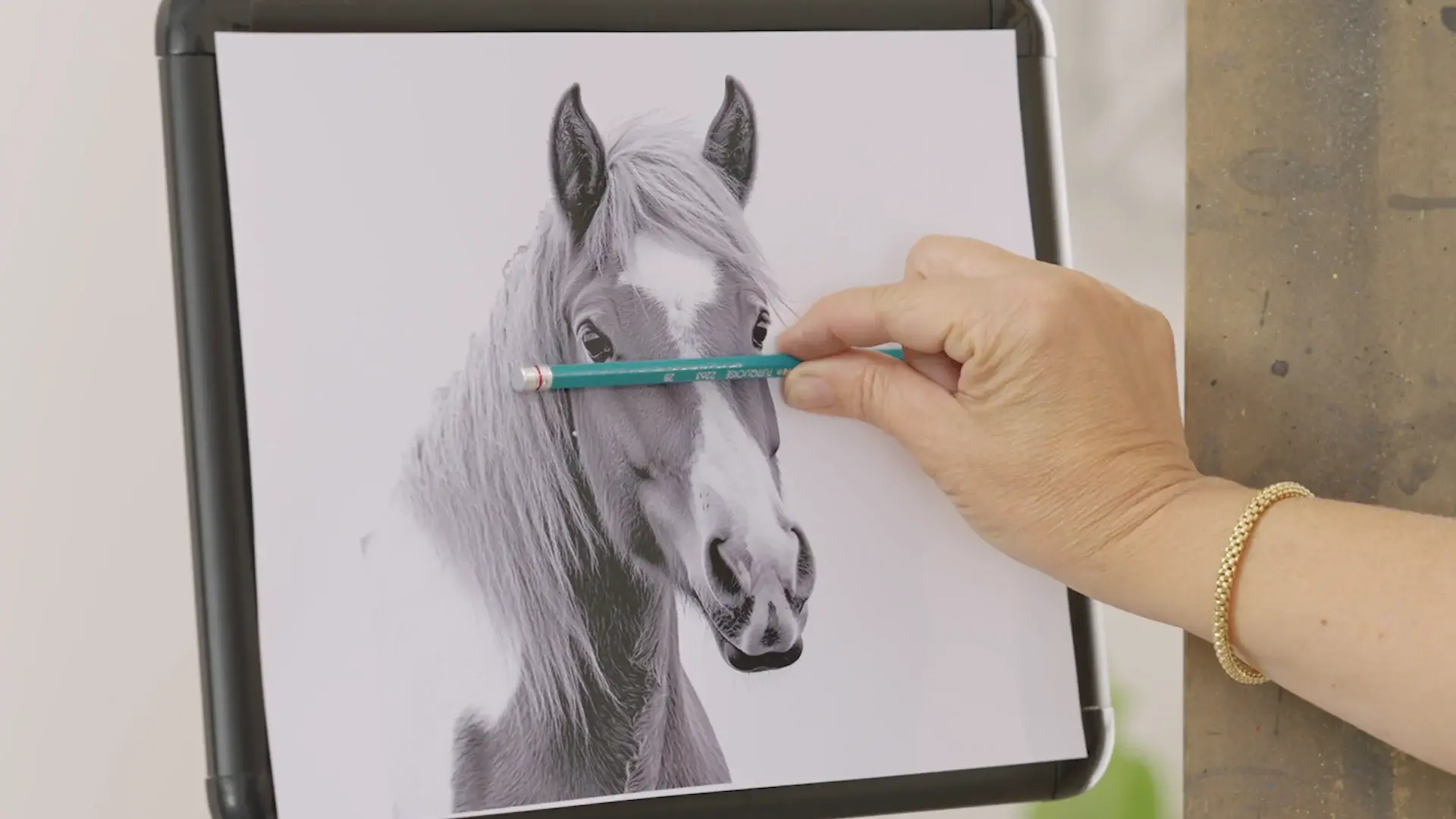A pencil held level across the horse reference photo to read an angle